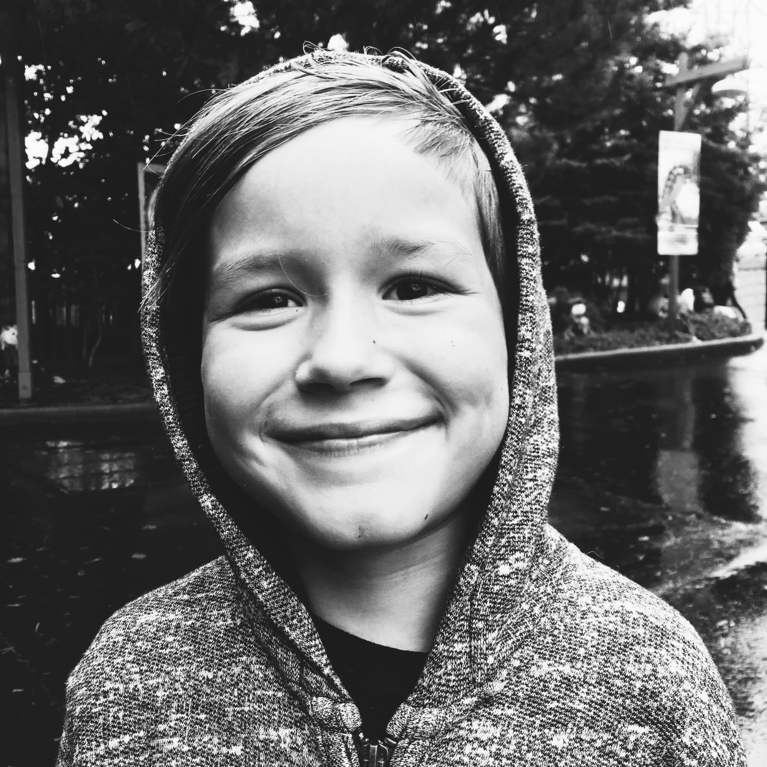 young kid smiling in a hoodie in the rain