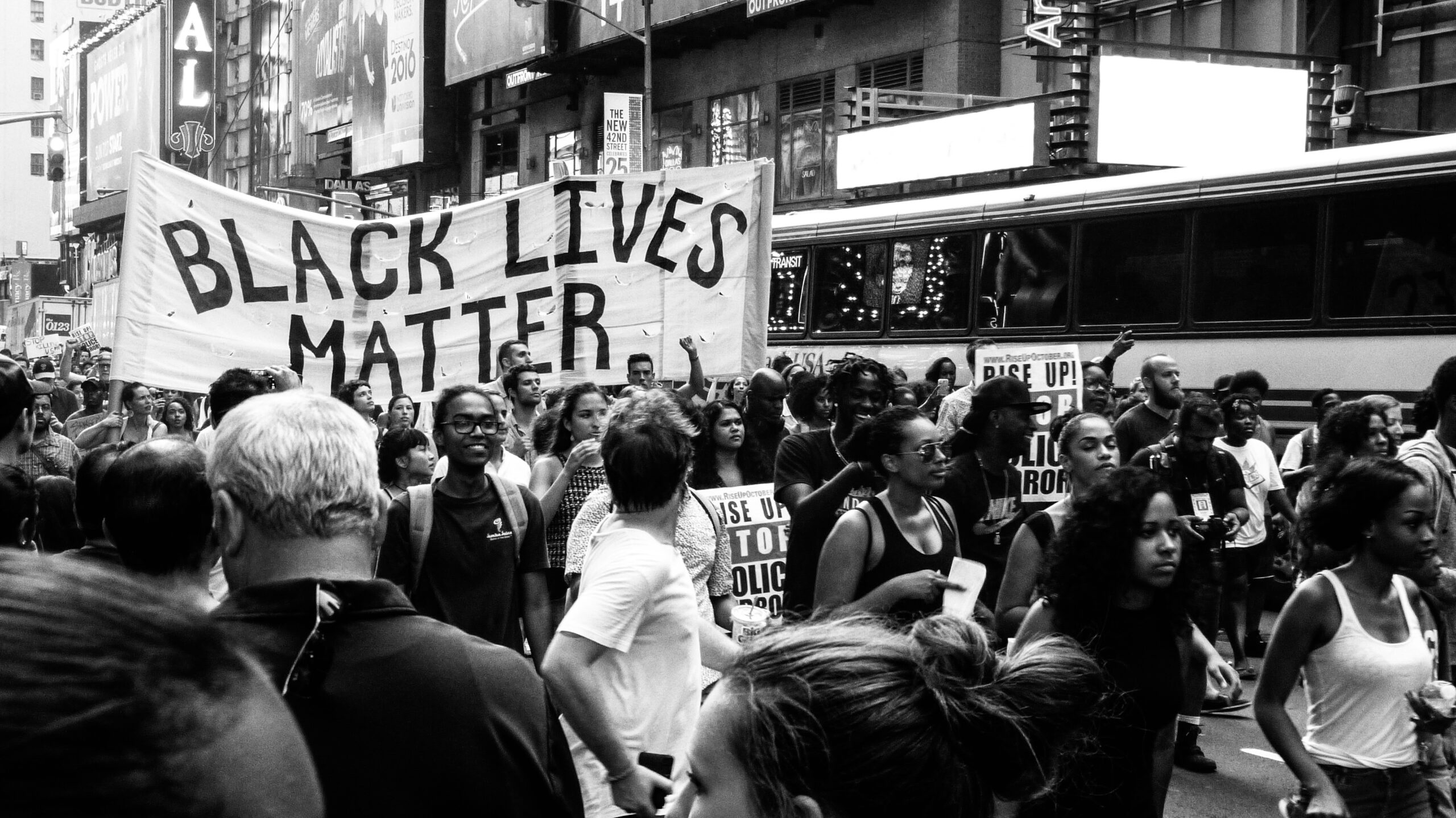 people march in the streets carrying a Black Lives Matter banner